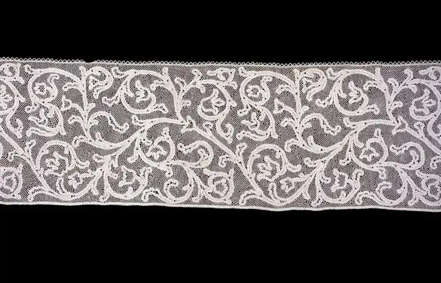Wide band of white scrolling lace on a dark background