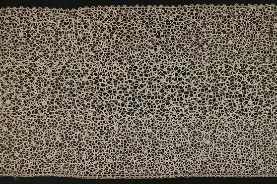 Two lengths of cream-coloured vintage lace flounce showing a dense openwork pattern
