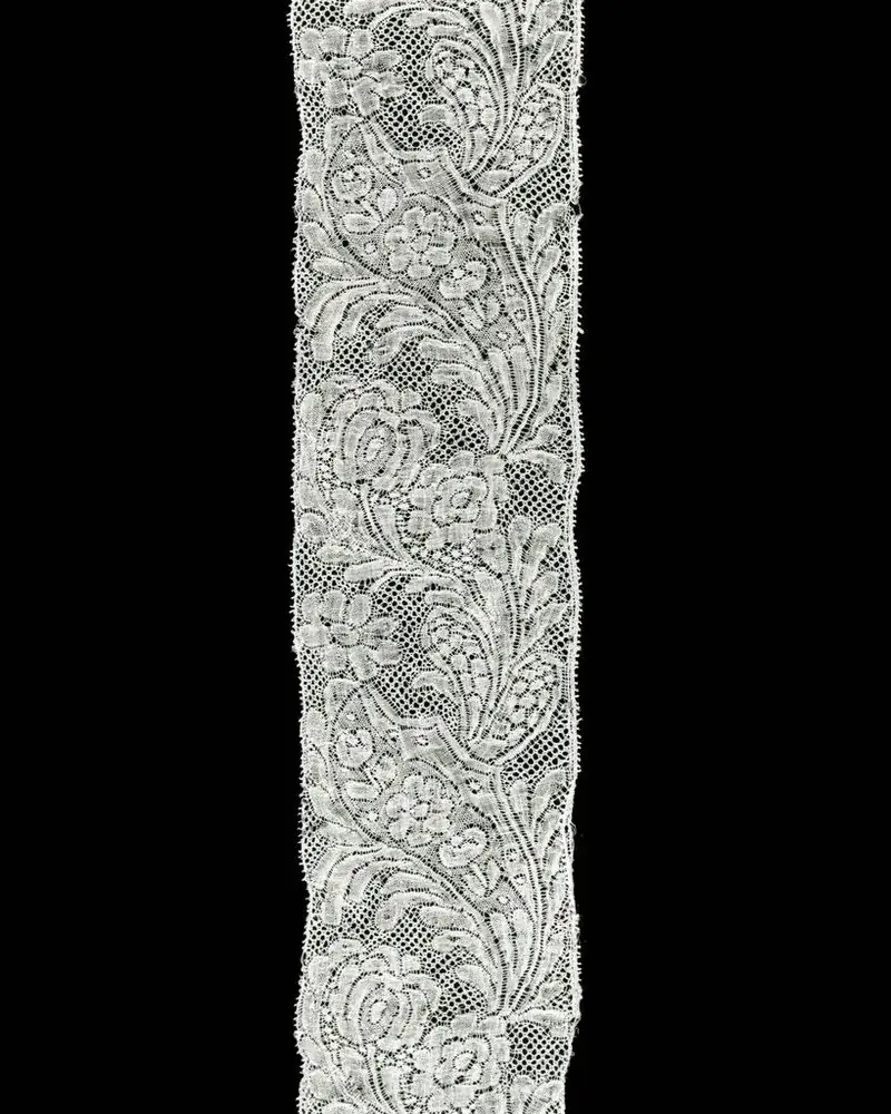 Narrow strip of white floral lace on a black background