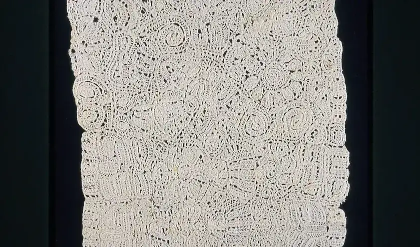 Close view of ivory lace textile with an intricate raised pattern
